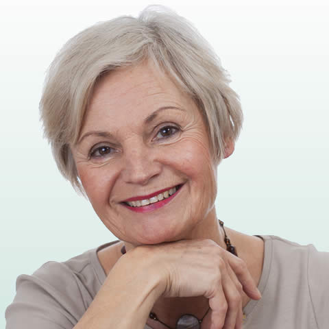 Smiling older lady resting her chin on her hand.